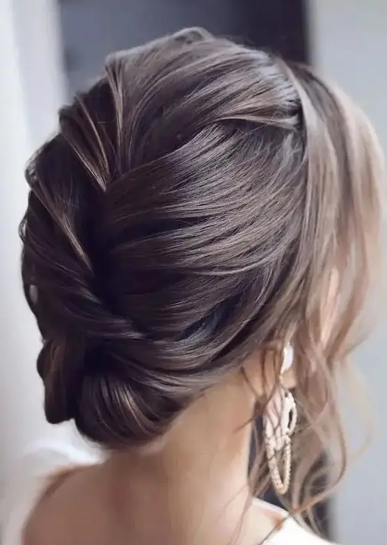 an elegant and sophisticated wedding updo with a braided back with volume and some locks framing the face is a cool and chic idea