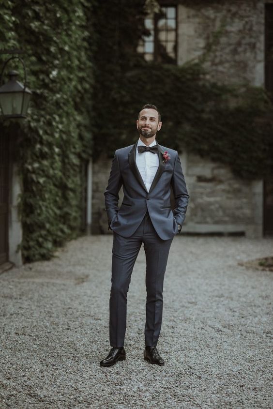 an elegant grey groom's tuxedo with black lapels, black shoes and a black bow tie plus a bold boutonniere