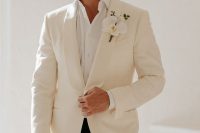 an elegant groom’s look with a white shirt, a white tux and black pants plus an orchid boutonniere for a tropical wedding
