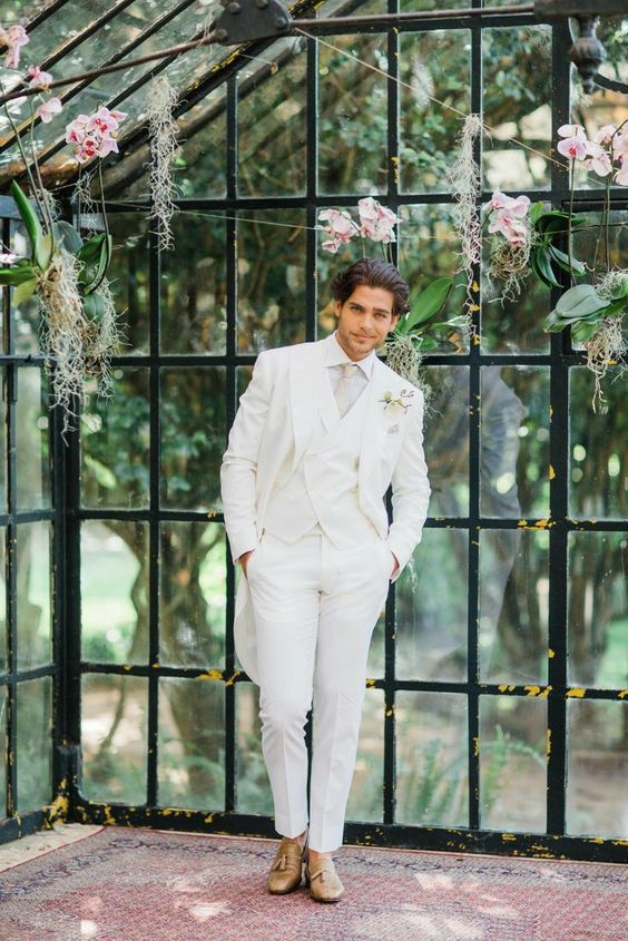 an elegant groom's outfit with a white three-piece suit, a white shirt, a neutral tie and brown shoes will match many wedding themes and styles