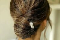 an elegant twisted low chingon with a volume on top and some pearl hair pins is classic for a wedding