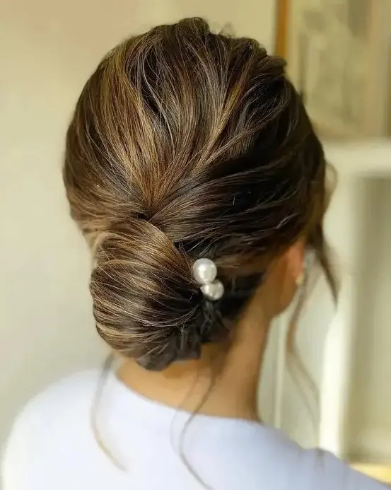 an elegant twisted low chingon with a volume on top and some pearl hair pins is classic for a wedding