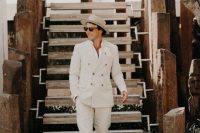an off-white suit and a white shirt, brown moccasins and a hat are a perfect look for a tropical wedding