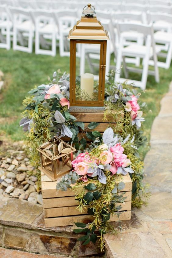 bright and cool rustic wedding decor with crates, blooms and greenery and a candle lantern for the ceremony space