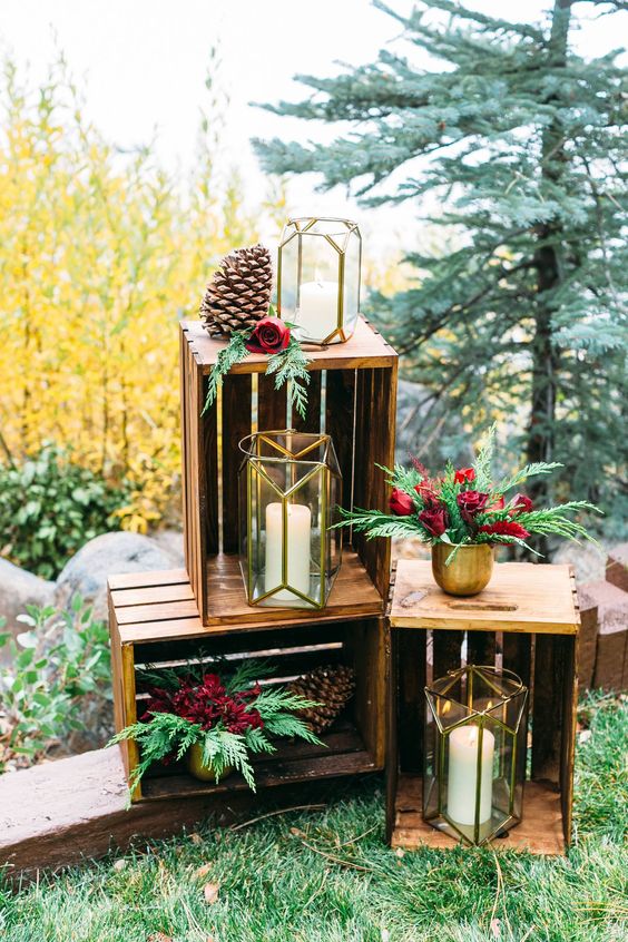 bright wedding decor with crates, greenery and burgundy roses, candle lanterns and large pinecones