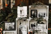 rustic wedding decor of white crates, with photos, greenery and candle lanterns is super cool and chic
