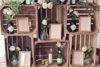 simple and cool wedding decor of crates, neutral blooms and greenery in liquor bottles and candles is cool