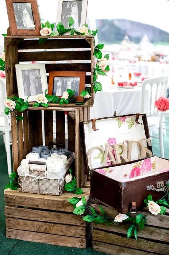 wooden crates with suitcases, greenery and blooms and vintage family photos will be nice rustic or backyard decor for a wedding