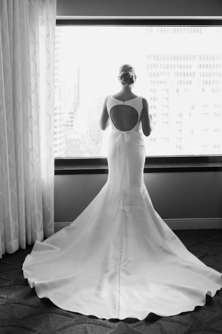 The bride was wearing a plain mermaid wedding dress with a cutout back and a row of buttons on the back