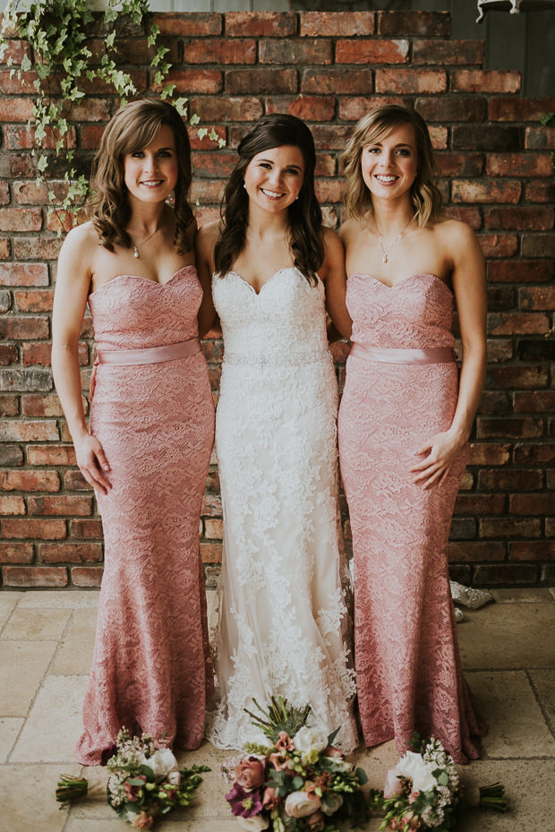 The bride was wearing a lace strapless sheath wedding dress, and the bridesmaids were wearing similar gowns in pink