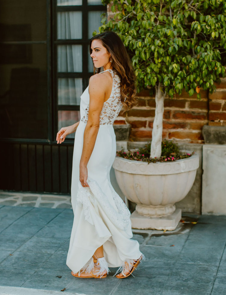 The bride was wearing a sheath wedding dress with a lace back, a halter neckline and fringe sandals
