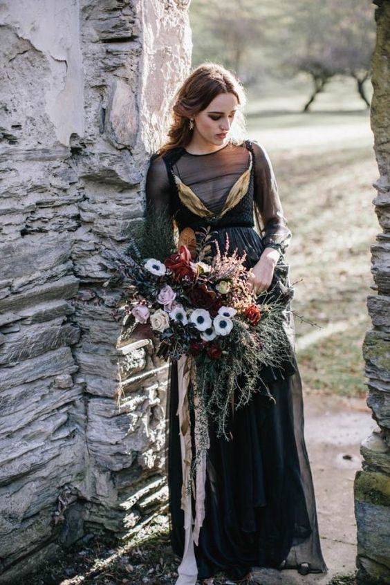 a black wedding dress with an illusion bodice and sleeves, gold detailing and a layered skirt