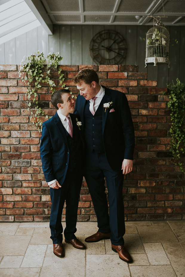 The groom and groomsman were rocking classic navy three-piece suits with pink touches