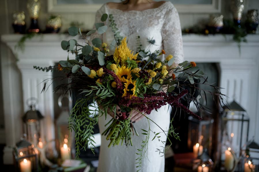 The wedding bouquet was done with textural and cascading greenery, burgundy and yellow blooms to embrace the fall