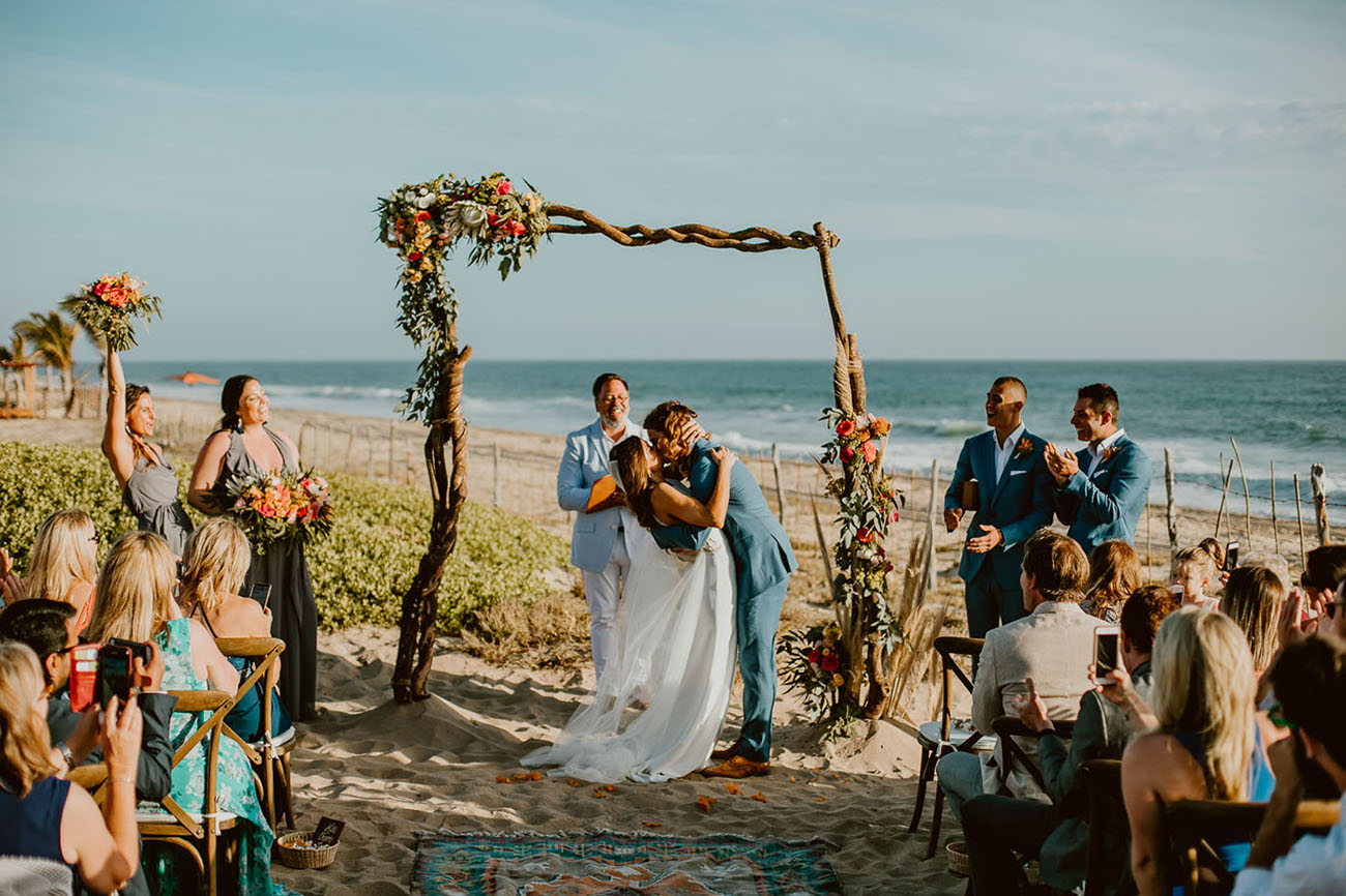 The wedding ceremony took place on the beach, the arch was amde of driftwood and decorated with bright flowers