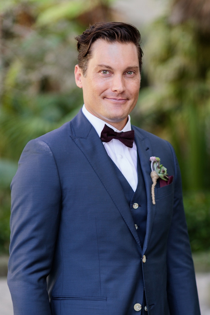 The groom was wearing a navy three-piece suit with a plum-colored bow tie and a succulent boutonniere