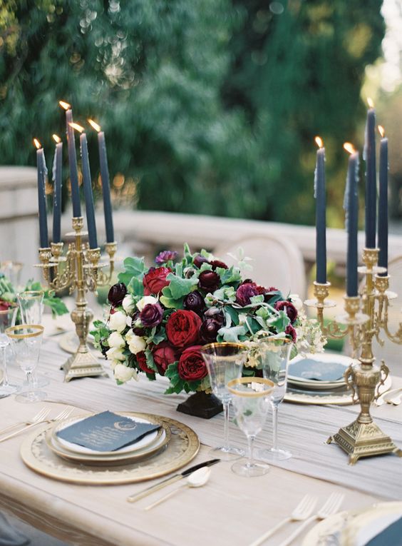 an elegant moody wedding centerpiece of white, ruby red and plum colored blooms and greenery