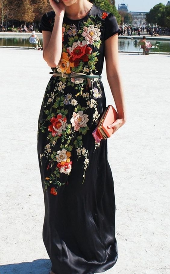 a black maxi gown with embroidered flowers, a coral clutch and a belt for a chic fall look