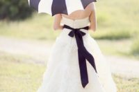 09 a white dress with a black sash and a matching black and white striped umbrella for a rainy day bride