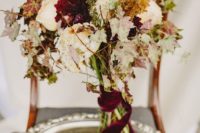 11 a messy fall wedding bouquet with blush, white and burgundy blooms, herbs and fall leaves plus a burgundy velvet ribbon