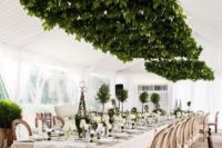15 an oversized fresh greenery overhead decoration and matching green centerpieces on the table