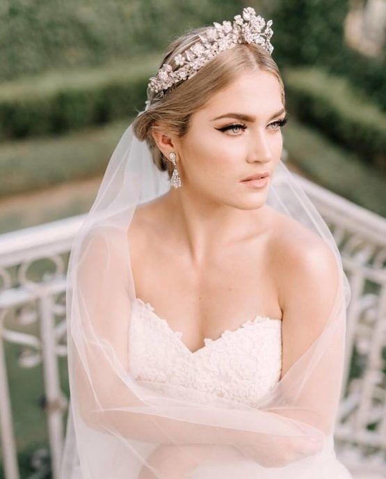 a statement floral rhinestone bridal tiara with a long veil plus rhinestone earrings for a glam feel