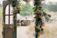 16 a wedding gate decorating with magnolia and colorful fall leaves and some grasses and an emerald ribbon