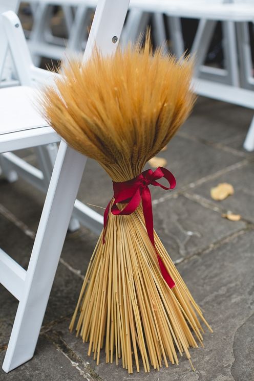 a fall wedding aisle marker of wheat with a plum-colored ribbon is ideal for a rustic wedding