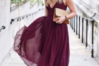20 a burgundy A-line midi dress with a V-neckline, a flowy skirt, nude  shoes and an embellished clutch