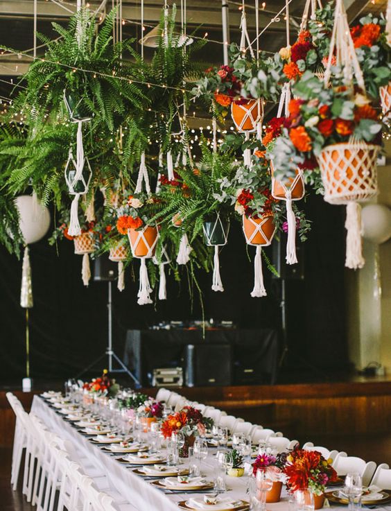 a creative overhead decoration with pots in macrame hangers and flowers and greenery for a boho wedding