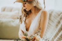22 a desert-inspired bridal look with a plunging neckline wedding dress and a brown hat topped with cacti and a bloom