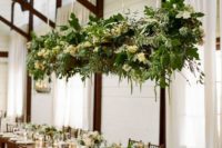 22 a hanging greenery and white bloom decoration over the reception and matching floral arrangements on the table