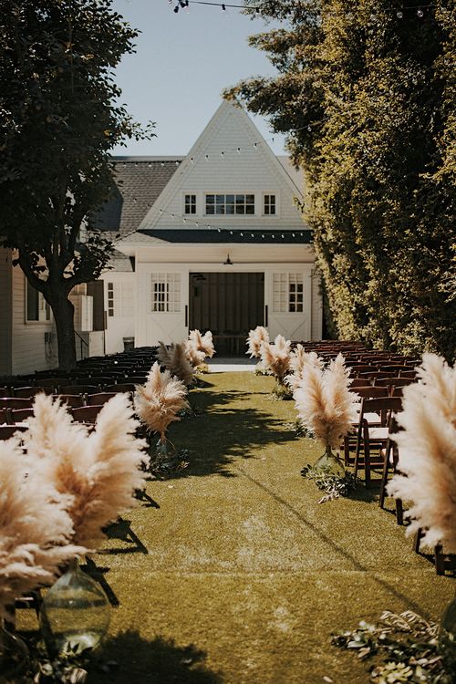 pampas grass in glass vases to line up the aisle for a fall boho wedding