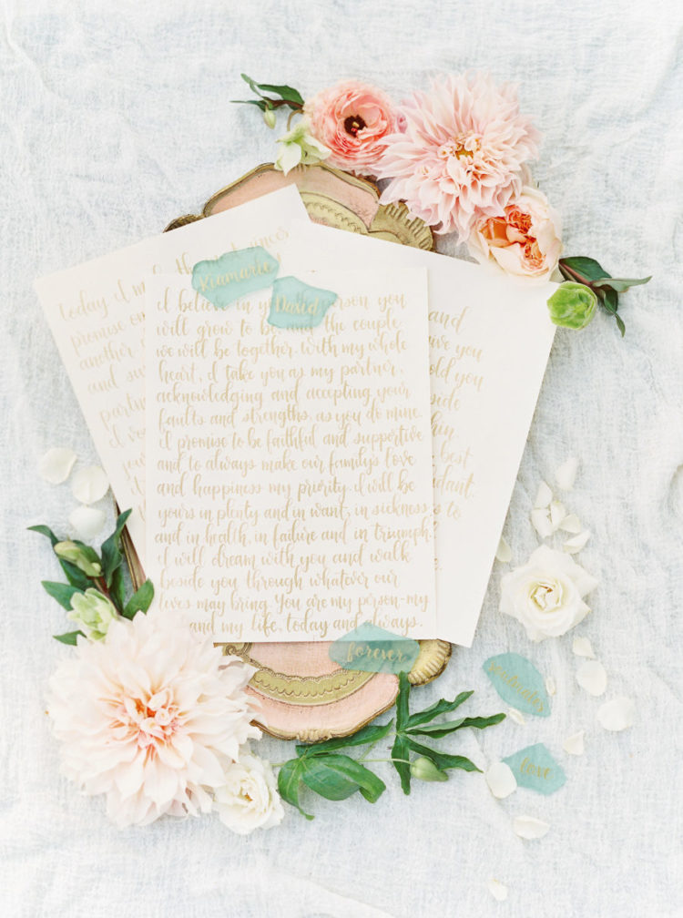 Here are wedding vows, chic gold calligraphy served on a tray with blooms