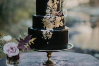 03 a black wedding cake with gold touches and feathers plus blooms is a classic Halloween idea