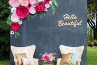 04 a simple photo booth with a chalkboard wall with pink paper blooms and comfy chairs