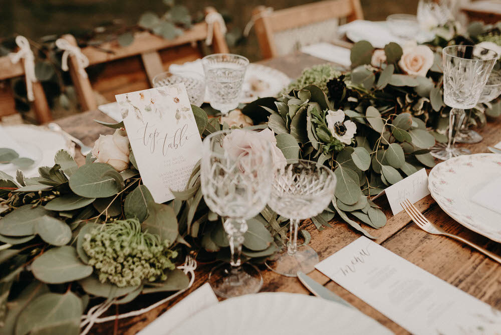 The wedding tablescape showed off a fresh greenery runner with blush blooms and floral table names
