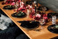 12 a chic moody tablescape with black plates and chargers, black candles, lush red and pink blooms right on the table