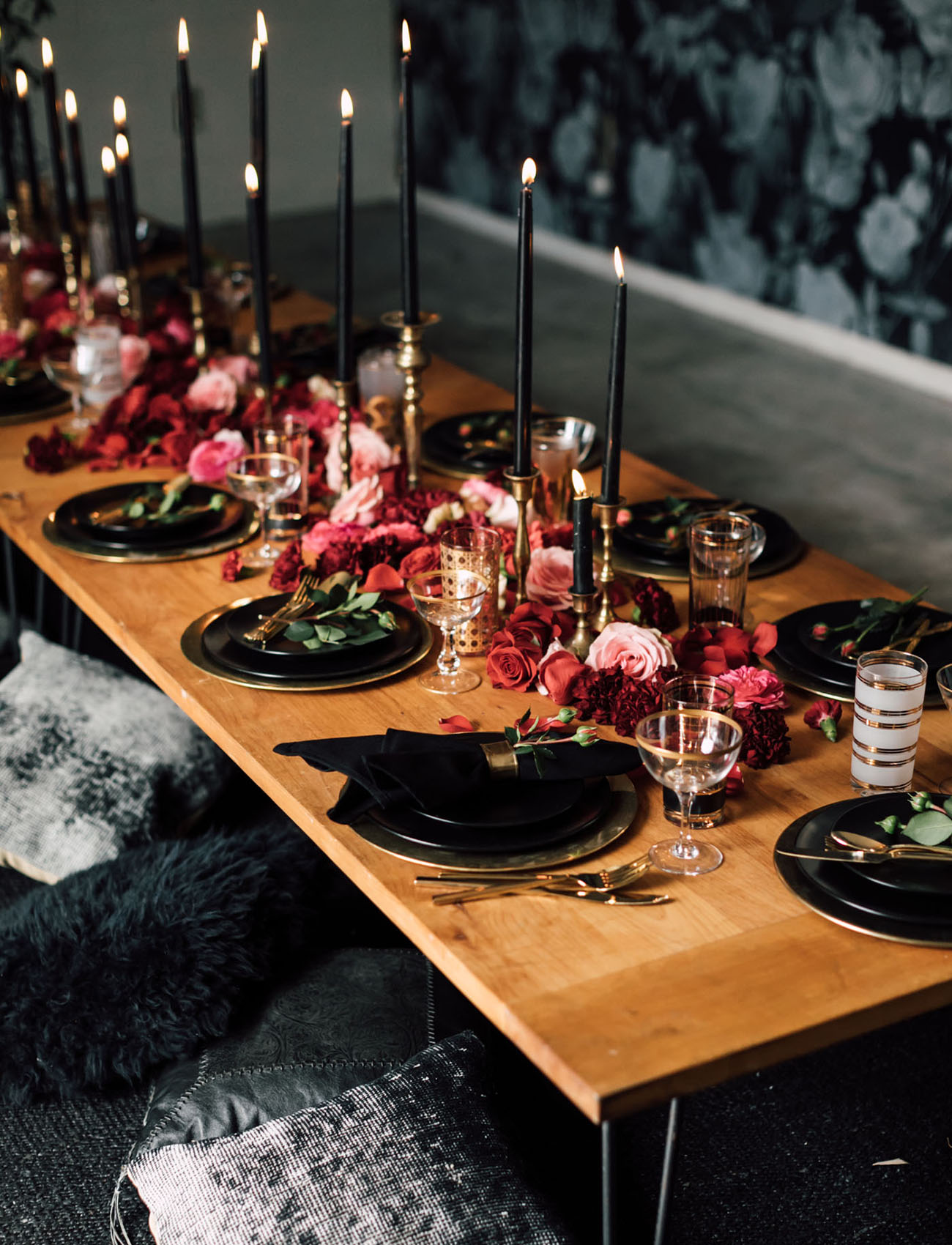 a gorgeous boho Halloween table setting with pink and burgundy blooms, black plates and candles and gilded touches