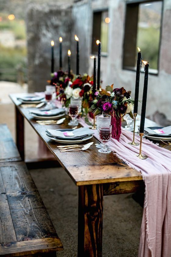 a moody tablescape with a pink table runner, black candles and gilded touches plus dark blooms