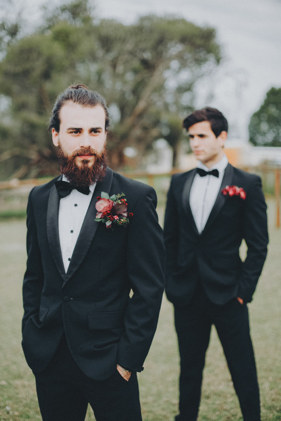 A classic black tux with a white shirt with black buttons and a bold redand burgundy boutonniere