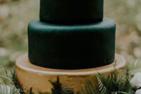 16 a moody Halloween wedding cake with a gilded tier and black ones, topped with greenery