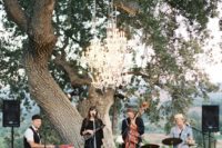 17 a cool wedding band playing outdoors on a separate podium accented with a glam chandelier
