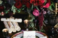 17 a luxurious moody table setting with a lush floral centerpiece, black candles and glasses and gilded touches
