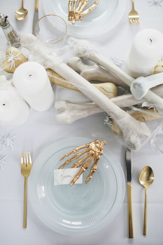 a stunning all-white tablescape with faux bones and spiders and gilded touches