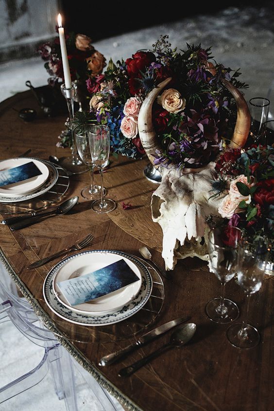 a luxurious decadent wedding centerpiece done with a skull and dark florals in purple, blue, deep red and blush