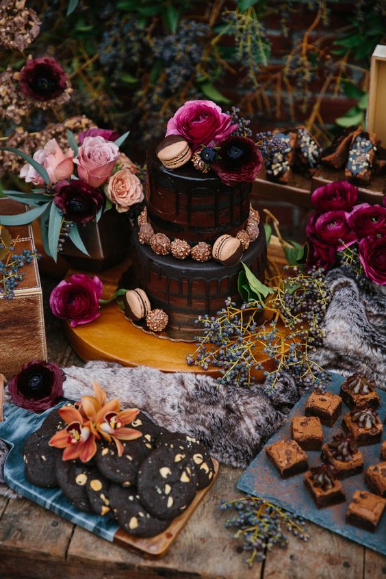a moody dessert table with a naked cake, chocolate and cookies and fuchsia and pink blooms