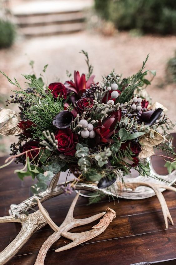 a moody Halloween centerpiece with deep purple and burgundy blooms, berries, textural greenery and foliage