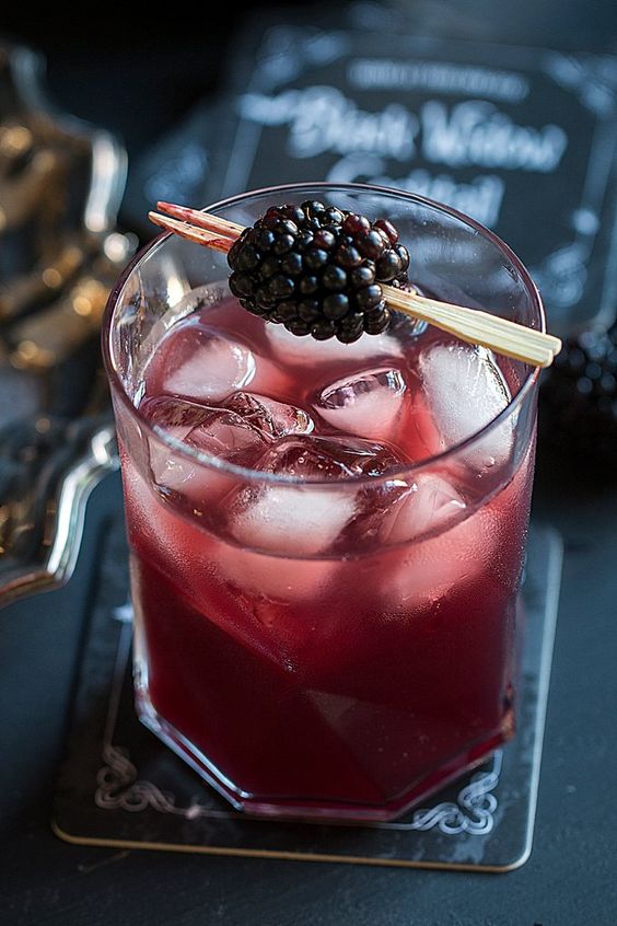 black window cocktail  of juice and vodka served with a blackberry