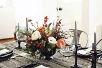 25 a rustic Halloween tablescape with a raw weathered wood table, grey candles, black chargrers and a textural floral centerpiece